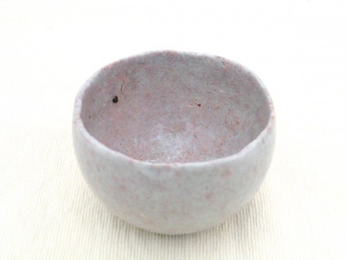 Pottery items such as this contemporary wabi-sabi tea bowl are often rustic and simple-looking, with shapes that are not quite symmetrical, and colors or textures that appear to emphasize an unrefined or simple style.