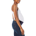 A stock photo of a pregnant person modeling a white maternity tank-top and blue denim jeans from Signature by Levi Strauss & Co.