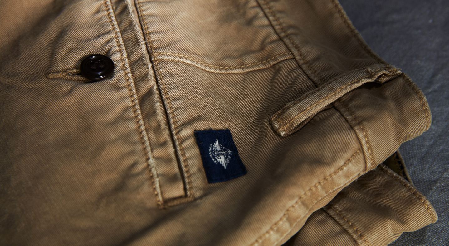 A close up shot of the back of a pair of tan Dockers® pants with a black Dockers® logo.