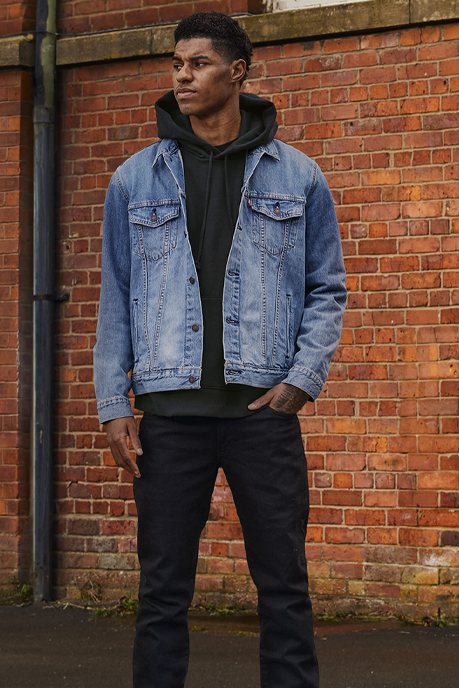 Marcus Rashford poses in a black Levi's® hoodie, a blue denim Levi's® Trucker jacket and black Levi's® pants for the Levi's® "Buy Better, Wear Longer" campaign