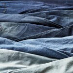 a pile of Levi's® denim jeans of various blue washes lie next to each other