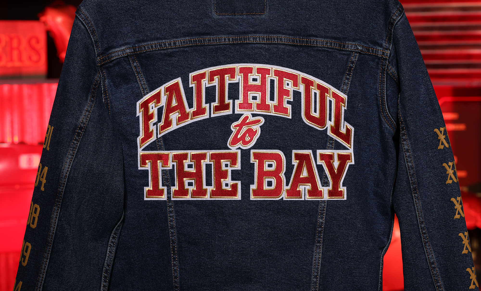 The back of a Levi's® x San Francisco 49ers jacket, reading "Faithful to the Bay" in all caps and red lettering.