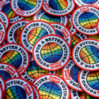 A pile of Levi's® patches that feature a red border with a rainbow colored circle design in the middle and the words "voting for a better future" around the center, as well as a red Levi's® batwing logo at the bottom center.