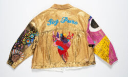 The back of a Levi's® Trucker jacket that has been painted gold. A human heart is painted in the center and the words "Soy Puro" in blue script. 