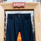 A pair of giant Levi's® 501® jeans hangs in a wooden frame with the red Levi's® batwing logo at the top.
