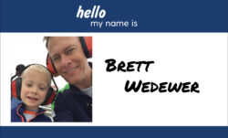 A name badge design. A blue header reads "hello my name is." Below, a selfie of Brett Wedewer and his child next to "Brett Wedewer" in black script.