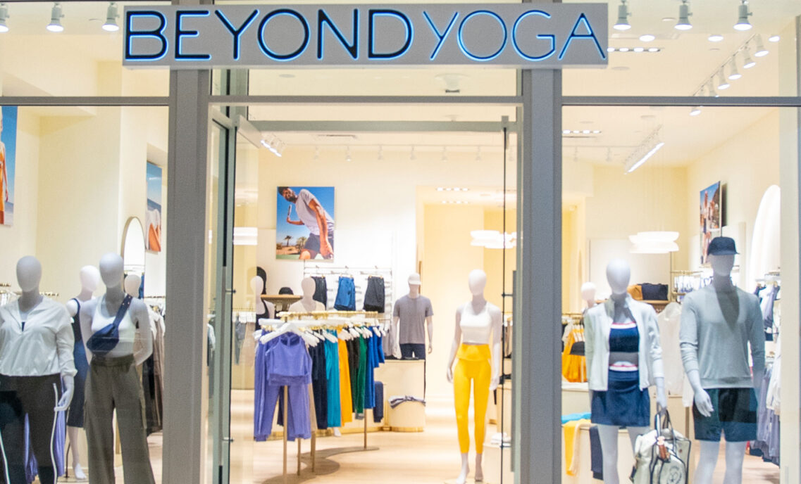 The exterior doors of Beyond Yoga® Bellevue in Seattle open to show assorted Beyond Yoga® products on mannequins and racks.