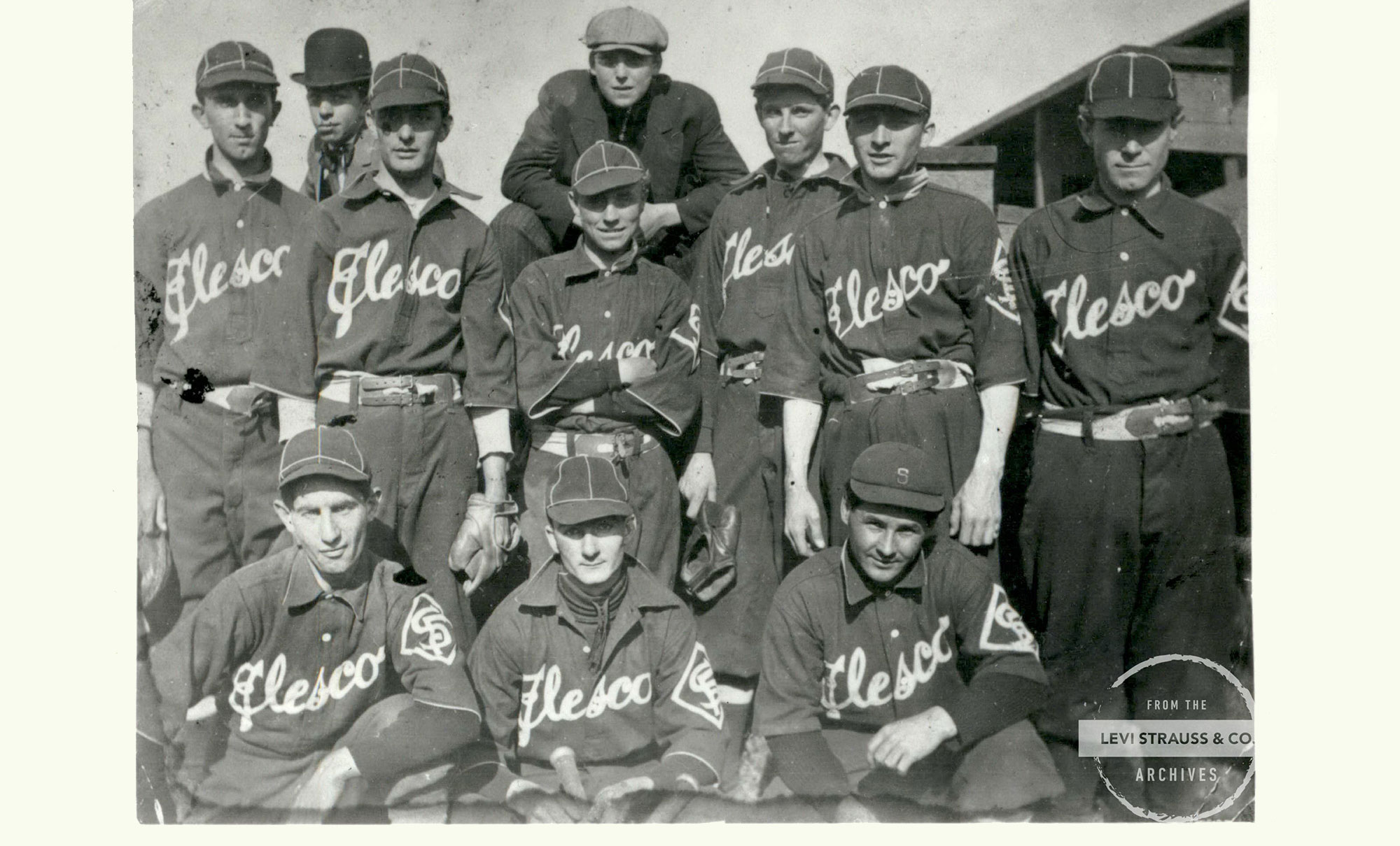 A black and white image of an early LS&Co. employee baseball team, Elesco. Players wear matching uniforms and hats.