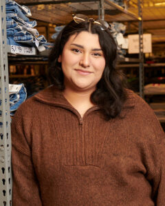 a portrait of a Levi's® retail employee posing in front of a shelf of Levi's® denim