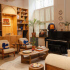 An interior space inside Haus of Strauss London, featuring built in shelves, arm chairs, coffee table, piano and sofa.