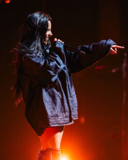 Music artist Jessie Murph wears a custom studded Levi's® denim jacket and sings into a microphone at the Community College Concert Competition Concert in Austin, 2024