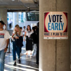 A person wearing a "Vote" T-shirt walks next to a column featuring a poster reading "Vote Early"