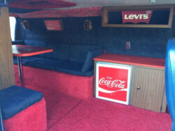 The interior of the Ford "Denim Machine" featuring plush red carpet, blue upholstered seating, a Levi's® logo and a Coca-Cola branded minifridge.