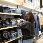 A person grabs a pair of jeans from a wall of stacked jeans in a Levi's® store