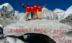 Four LS&Co. employees wear red Levi's® T-shirts on top of a large boulder that reads "Everest Base Camp 5364m"