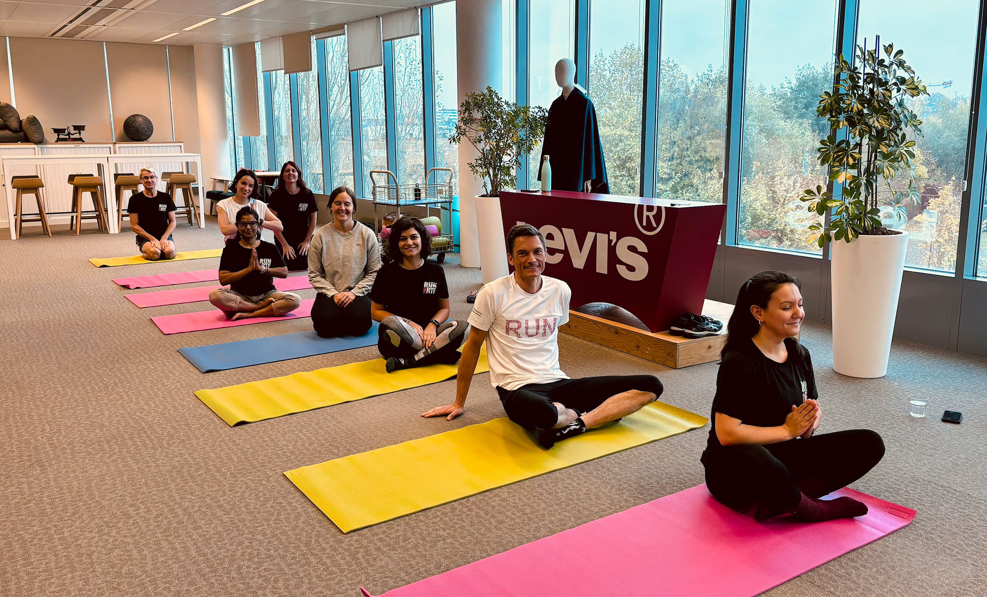 Eight LS&Co. employees pose on their yoga mats as they get ready for a group yoga class to support the 2024 (Run) for Red Tab