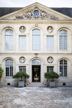 The two story front facade of the Levi's® Haus of Strauss Paris, featuring Parisian architecture and a stone-paved courtyard.