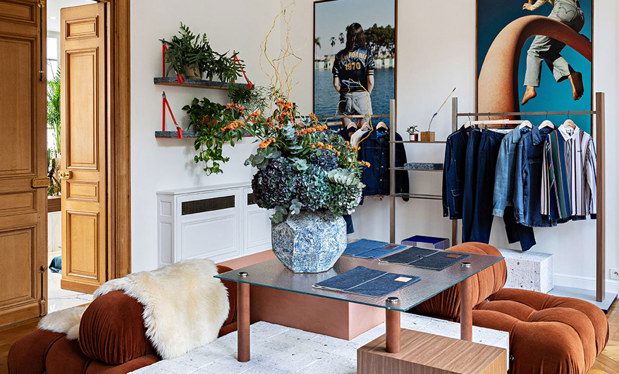 Interior of Levi's® Haus of Strauss Paris featuring plants, racks of Levi's® products, a glass table, organ plus chair and floral centerpiece.