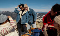 A Levi's® holiday campaign marketing photo shows a group of friends in a snowy mountain setting. One friend takes a photo of two friends posing wearing denim sherpa jackets.