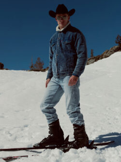 A Levi's® holiday campaign photo shows a person wearing a cowboy hat, corduroy sherpa lined jacket, blue jeans and a pair of skis on a snowy hillside