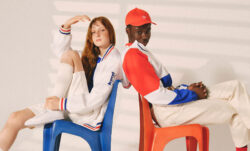 A model on the left sits on a blue chair and wears a white outfit from the Levi's® x Paris collection, featuring red and blue stripes on the sleeve cuffs. A person on the right sits on a red chair and models a red baseball had and a red, white and blue jacket from the Levi's® x Paris collection.