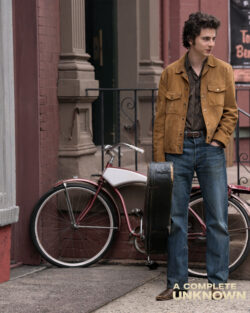 Timothée Chalamet as Bob Dylan stands by a bicycle wearing a suede jacket and Levi's® blue jeans