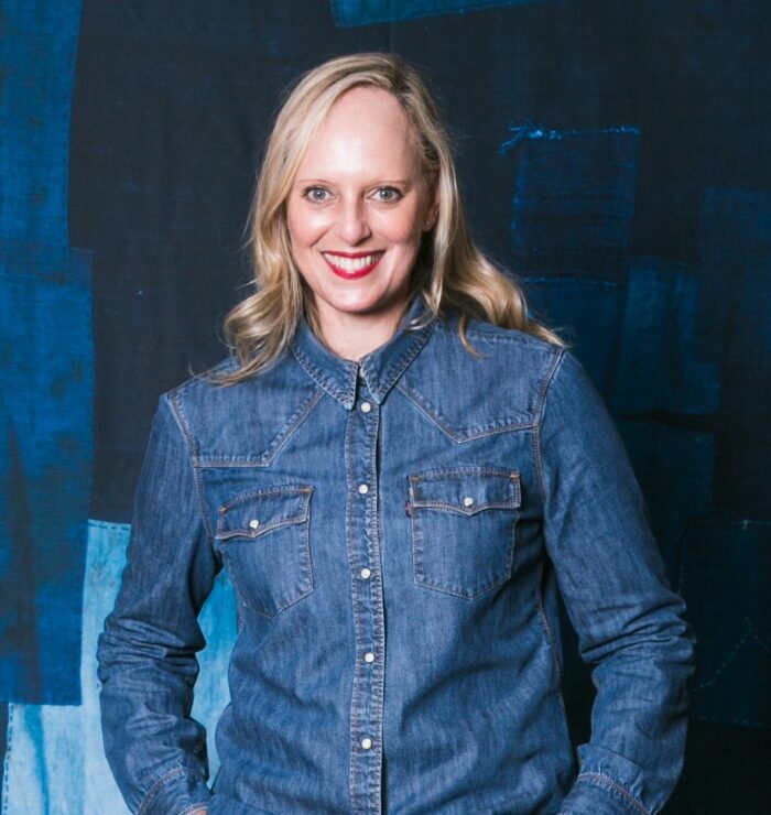 Dominique Durward, the first LS&Co. employee hired in South Africa, poses for a headshot in a denim button down shirt against a blue background.