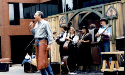 Former LS&Co. CEO Bob Haas stands on stage and speaks into a microphone in front of a mariachi band