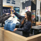 A person reaches for a Levi's® tote bag from a Levi's® retail worker as they checkout at a Levi's® store