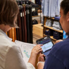 The back of two Levi's® store employees holding a scheduling sheet and referencing an electronic tablet