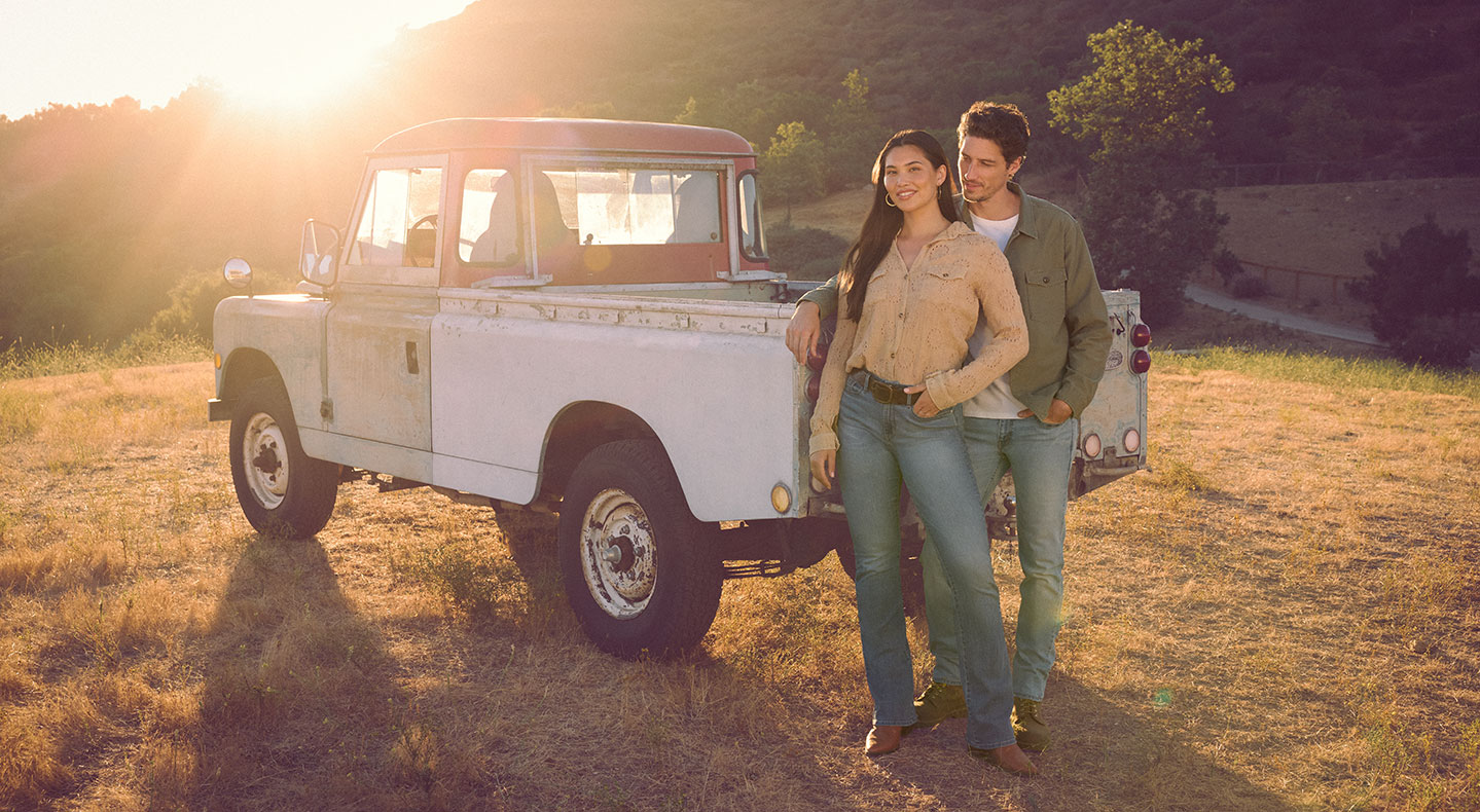 Two people stand in a field leaning against a pick up truck wearing Levi Strauss Signature clothing