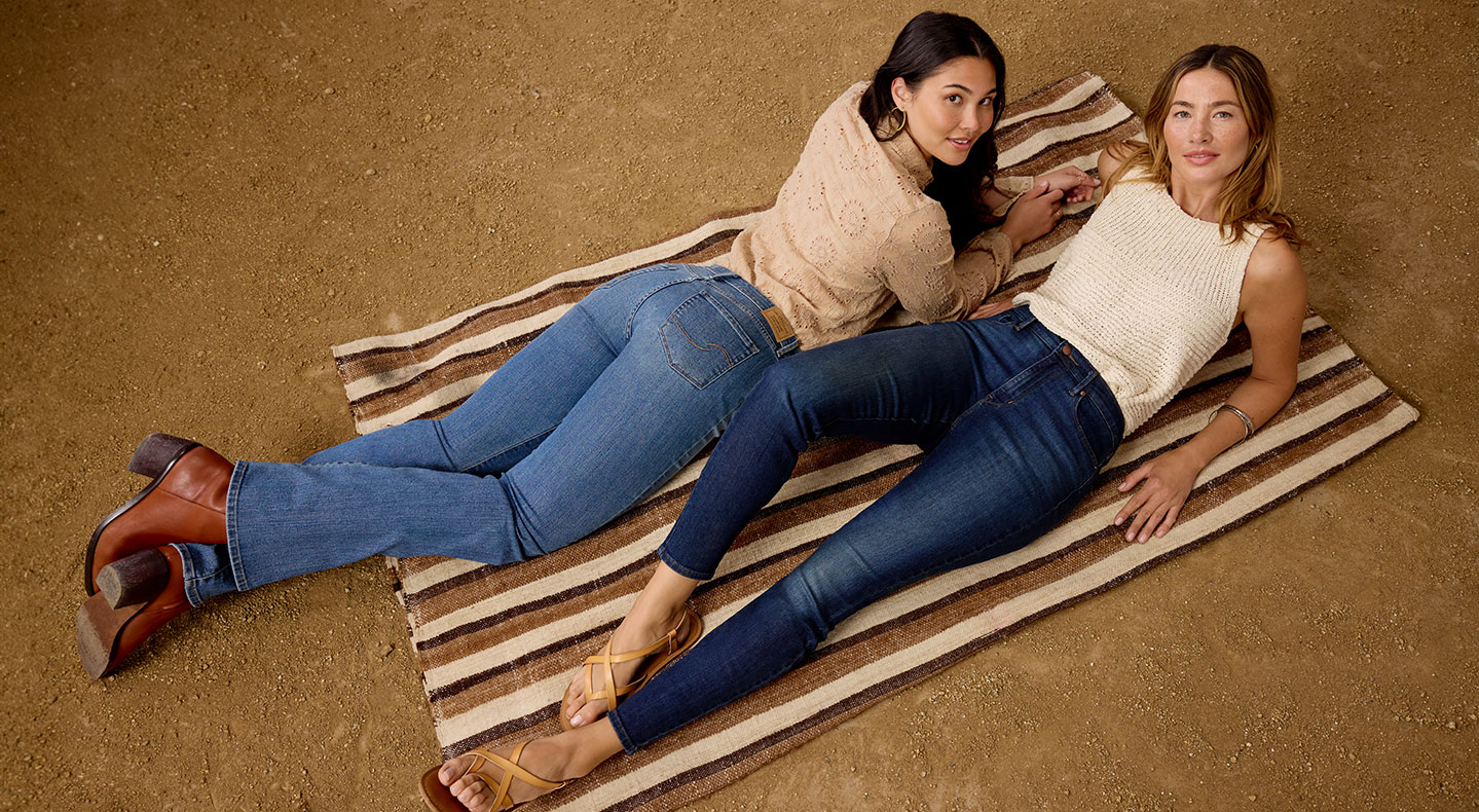 Two people lay on a picnic blanket and smile at the camera wearing Levi Strauss Signature denim jeans