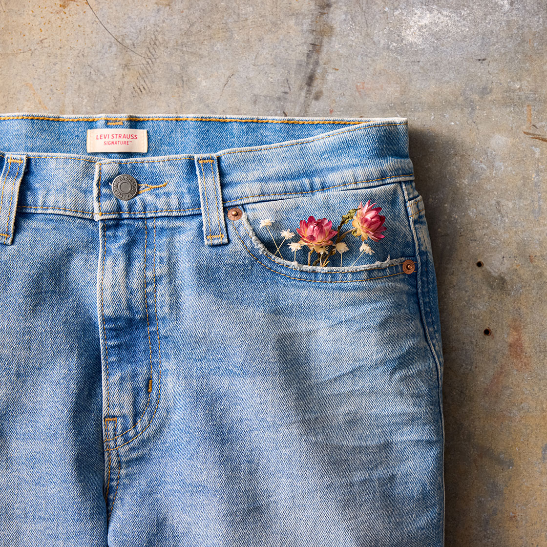 A close-up shot of a pair of Levi Strauss Signature light wash denim jeans with wildflowers in the right pocket