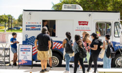 Community college students stand in line to receive free pizza and register to vote at a "Pizza to the Polls" food truck