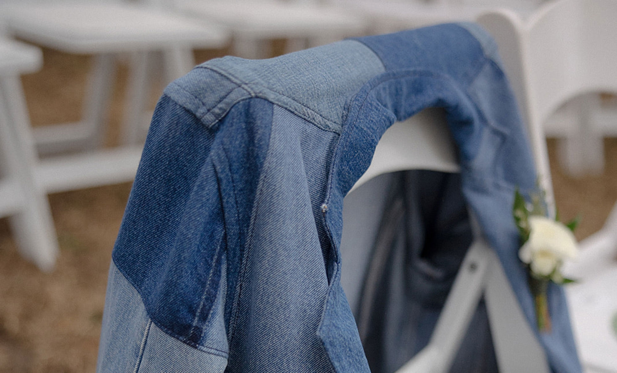 A patchwork denim jacket drapes on the back of a white chair