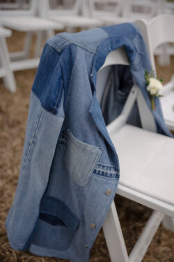 A patchwork denim jacket drapes on the back of a white chair