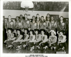 A black and white group image on a basketball court featuring the Harlem Globetrotters standing in the back and the Texas Cowgirls kneeling in the front.